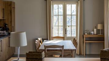 Een eetruimte met een tafel, stoelen, een lamp en een raam met gordijnen.