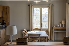 A dining area with a table, chairs, a lamp, and a window with curtains. - PASQUET 2 - ARTHEZ D'ARMAGNAC (ARTHEZ D'ARMAGNAC)