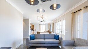 Ein modernes Wohnzimmer mit grauem Sofa, rundem Couchtisch und Pendelleuchten.