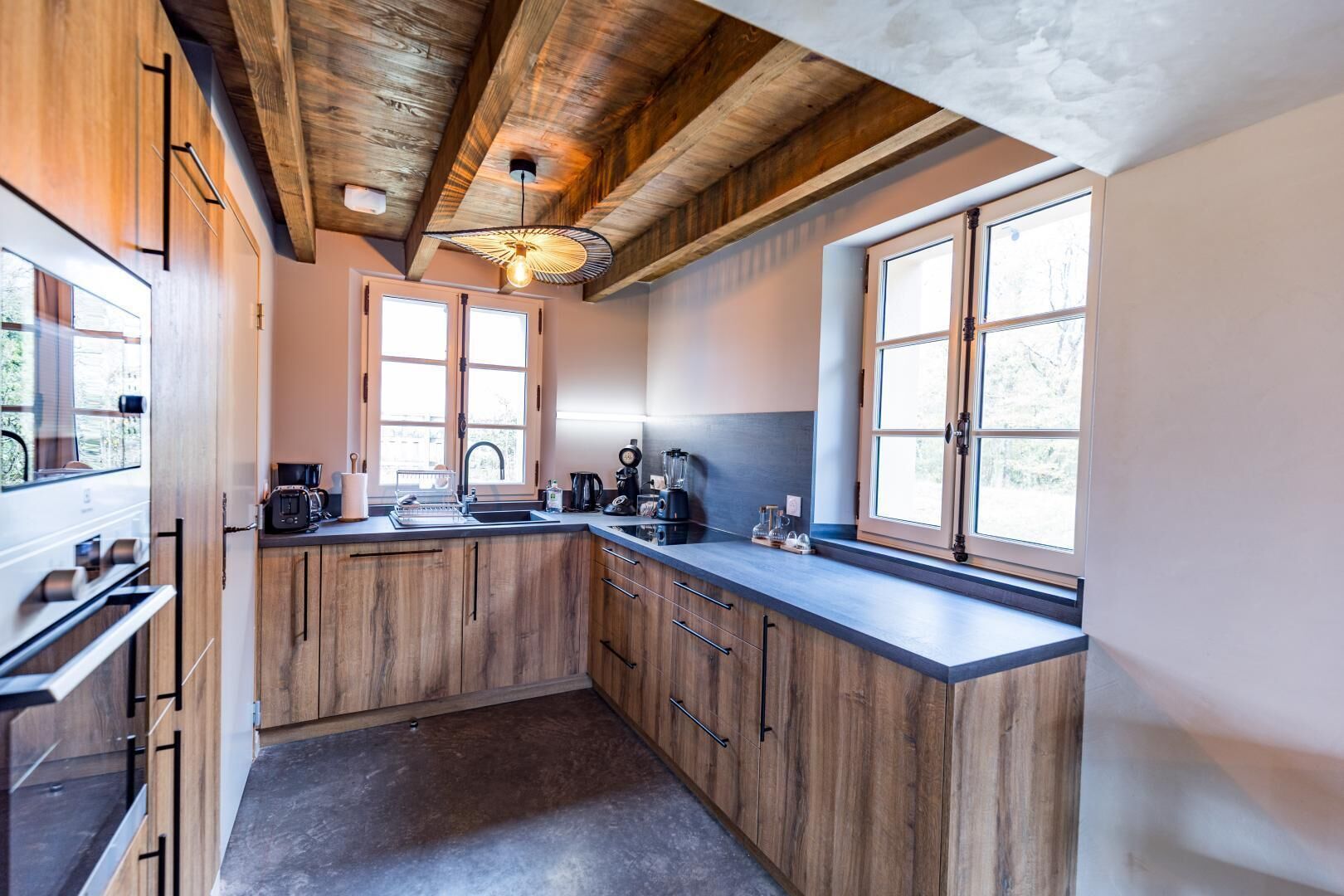Une cuisine avec des meubles de rangement en bois, un plan de travail, un évier et une fenêtre.