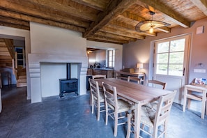 A rustic interior with a wooden table and chairs, a fireplace, and a kitchen area. - POUYLABRIN 3 - ARTHEZ D'ARMAGNAC (ARTHEZ D'ARMAGNAC)