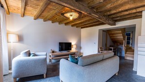 Una sala de estar con techo de madera, televisor, sofá y lámpara.