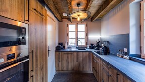 Una cocina moderna con armarios de madera, horno empotrado, cafetera y licuadora sobre la encimera.