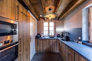 A modern kitchen with wooden cabinets, a built-in oven, a coffee maker, and a blender on the counter. - POUYLABRIN 3 - ARTHEZ D'ARMAGNAC (ARTHEZ D'ARMAGNAC)