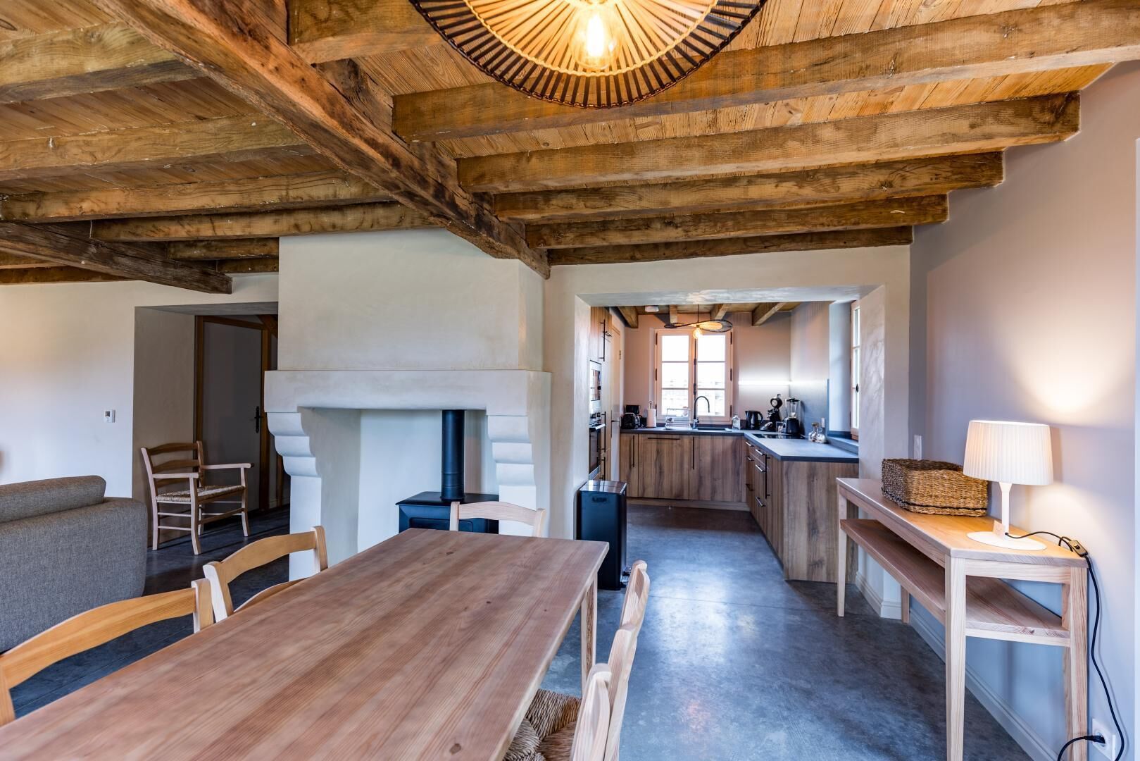 Un interno rustico con un tavolo da pranzo in legno, sedie, un camino e un angolo cottura.