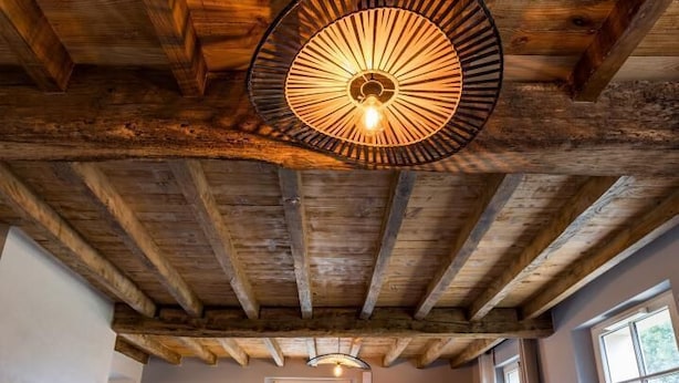 Una habitación acogedora con techo de madera, un sofá con cojines y un comedor al fondo.
