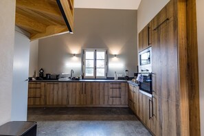 A kitchen with wooden cabinets, a window, and built-in appliances. - POUYLABRIN 2 - ARTHEZ D'ARMAGNAC (ARTHEZ D'ARMAGNAC)