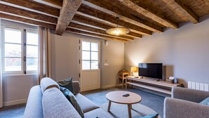 Un salon comprenant un canapé, des fauteuils, une table basse, un téléviseur et un plafond en bois.