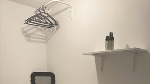 A white desk with a chair, a towel, a mirror, a lamp, and a hanging rack.