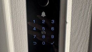 A black EZVIZ keypad lock installed on a white door.
