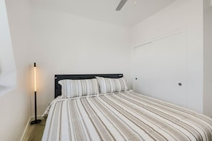 Ein Schlafzimmer mit einem Einzelbett, einer Nachttischlampe und einer weißen Tür.