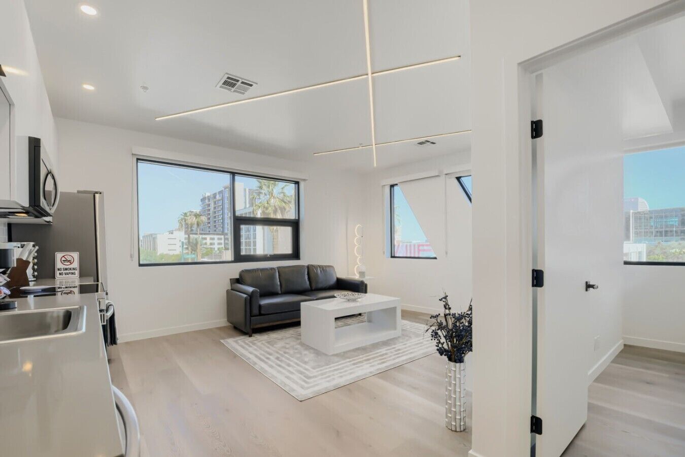 Ein modernes Wohnzimmer mit Sofa, Couchtisch und Blick auf die Stadt durch große Fenster.