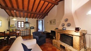 A cozy living room with a fireplace, a dining area with a table and chairs, and a kitchen with a tiled backsplash. - Villa Opera - Apartment in Florence (Toscana)