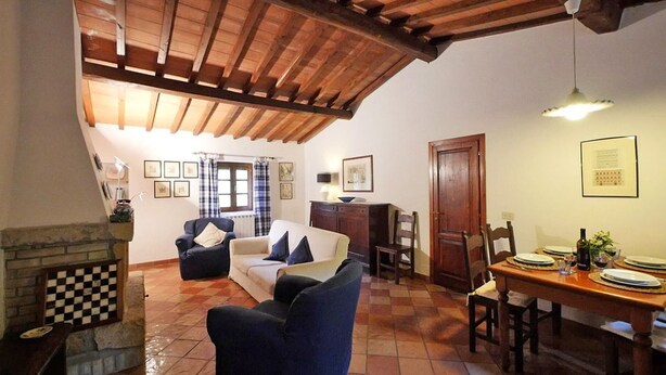 A cozy living room with a fireplace, a dining area with a wooden table set for two, and a checkered floor. - Villa Opera - Apartment in Florence (Toscana)