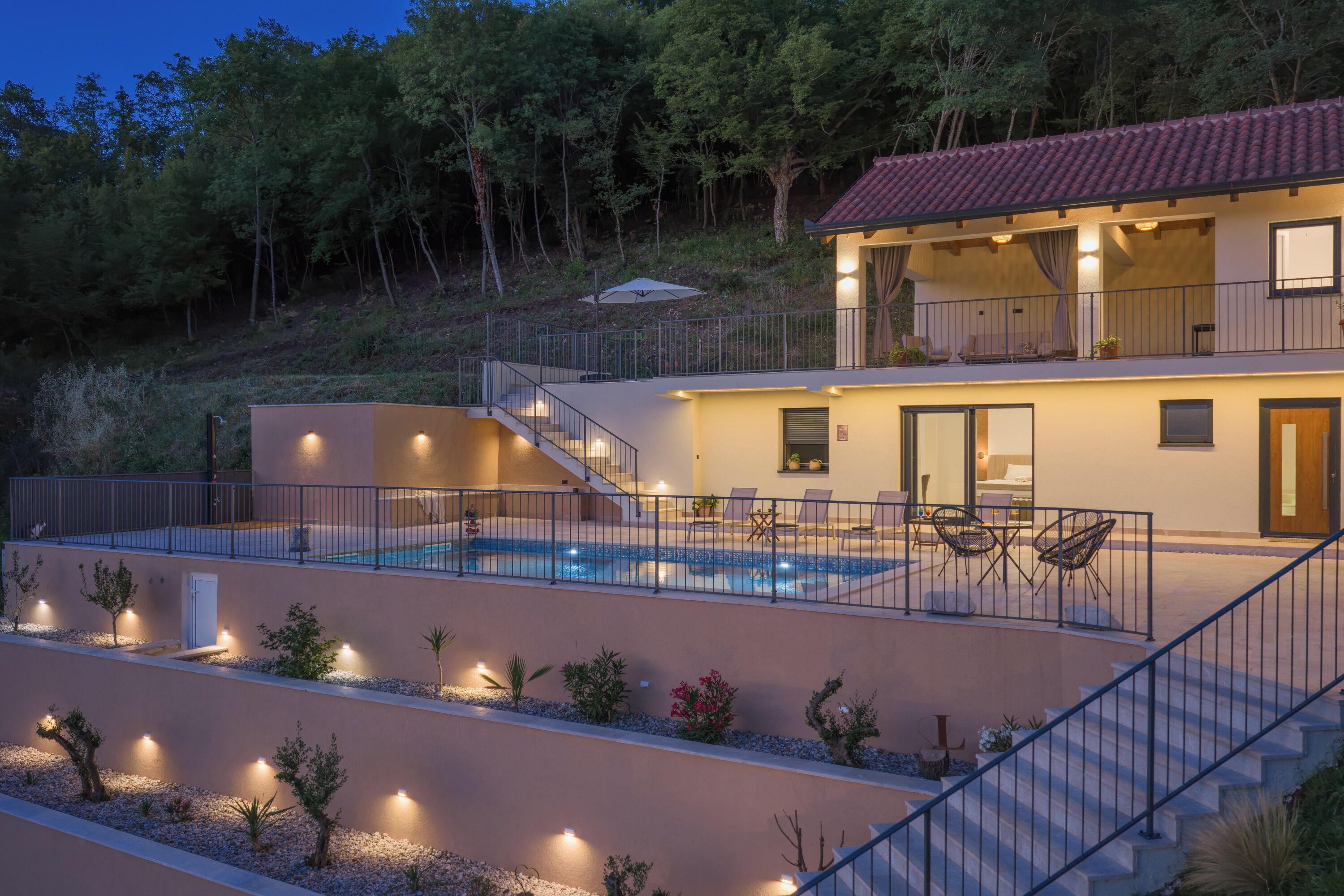 A modern two-story house with a swimming pool, outdoor seating, and a balcony.