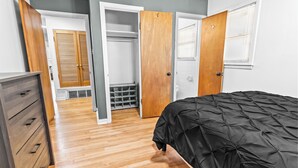 Quarto com cama, guarda-roupa de madeira e um armário com janela.