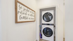 A laundry room with a wall-mounted sign and a front-loading washer and dryer. - Phoenix Rustic Urban Retreat (Phoenix)