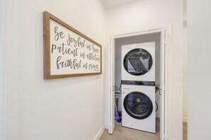 A laundry room with a wall-mounted sign and a front-loading washer and dryer. - Phoenix Rustic Urban Retreat (Phoenix)