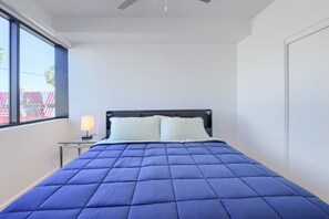 A bedroom with a bed, a nightstand, a lamp, and a window. - Phoenix Rustic Urban Retreat (Phoenix)