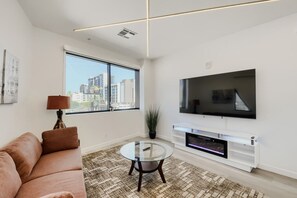 Ein modernes Wohnzimmer mit einer Couch, einem Glastisch, einem flachbildfernseher an der Wand und einem Kamin.