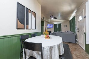 Een eetruimte met een ronde tafel, stoelen en een aan de muur bevestigde televisie.