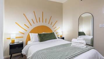 A hotel room with a bed, a nightstand, a mirror, and a wall decoration.