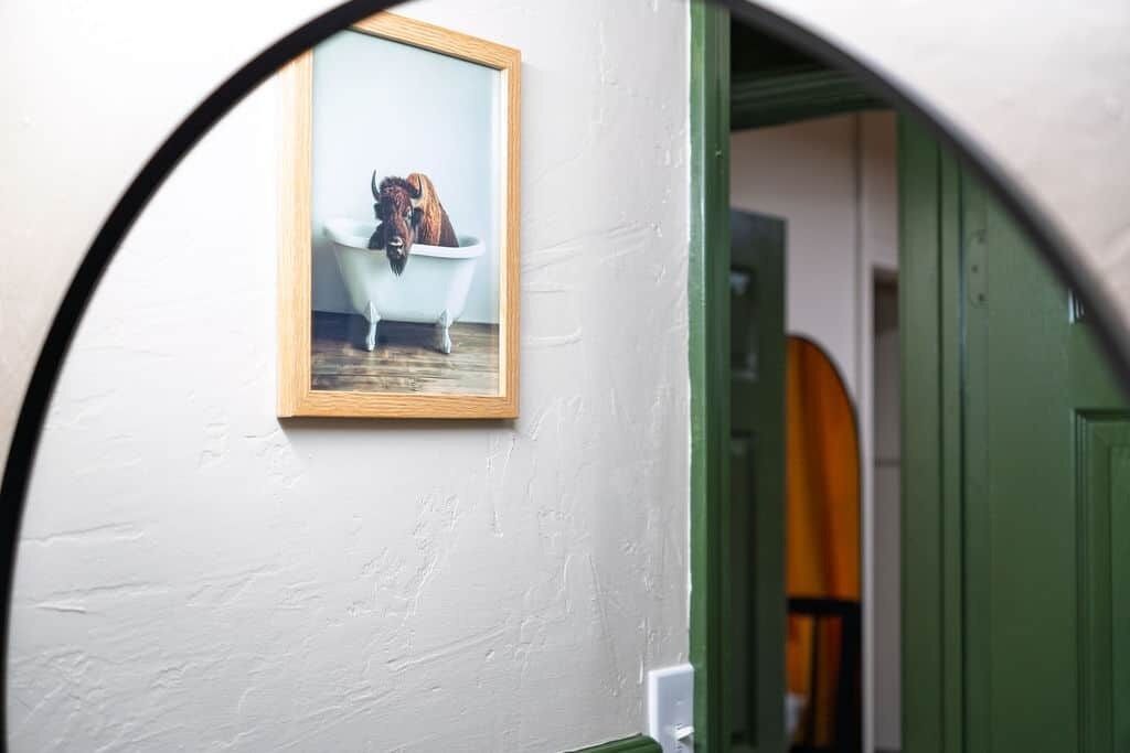 Een lijst met een afbeelding van een bizons in een badkuip, hangend aan een muur.