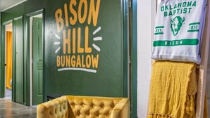 A room with a green wall, a yellow tufted chair, and a towel hanging on a rack. - Bison Hill Bungalow | 3 blks from OBU (Shawnee)
