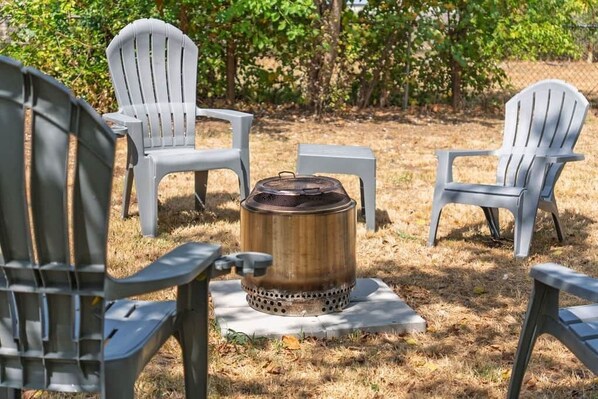 Terraza al aire libre con sillones Adirondack y una chimenea central.