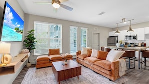 A modern living room with a sofa, coffee table, and TV. - Luxe•King Suite Universal/Epic•6 Min•Getaway (Orlando)