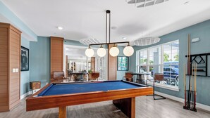 A pool table in a room with a wooden floor, a ceiling with recessed lighting, and a window with a view of the outside. - Luxe•King Suite Universal/Epic•6 Min•Getaway (Orlando)
