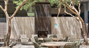 An outdoor seating area with tables and chairs, a fire feature, and a brick wall. - Phoenix Downtown Zen Loft (Phoenix)