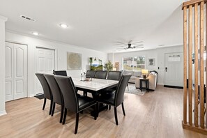 A dining area with a marble table and black chairs, a ceiling fan, and a view of the outdoors through a window. - Switchback Suites - Side A (Bentonville)