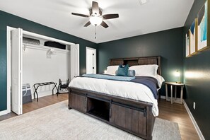 Ein Schlafzimmer mit einem Bett, einem Deckenventilator, einem Nachttisch und einer Tür zu einem Kleiderschrank.