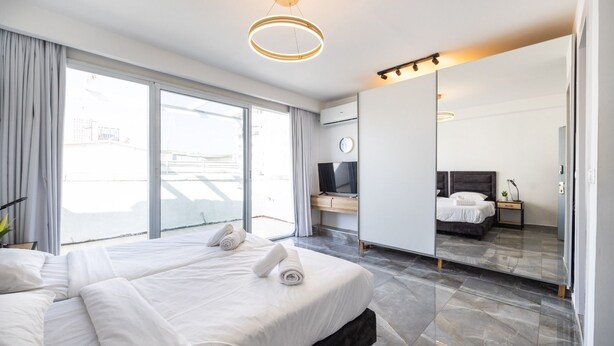 A modern hotel room with a large bed, a television, a desk, and a large mirror. - Premium and Luxe 2BR by the Shuk – Free Parking (Jerusalem)