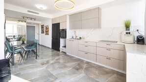 A modern kitchen with marble flooring, a dining area with chairs, and a pendant light. - Premium and Luxe 2BR by the Shuk – Free Parking (Jerusalem)