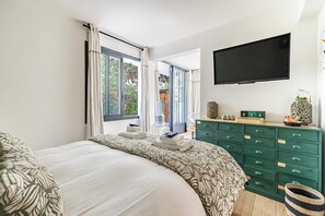 A bedroom with a bed, a dresser, a television, and a view of the outdoors. - Charming Apartment With Terrace a/c 4P - Cannes (Cannes)