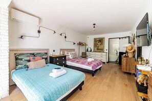 A bedroom with two beds, a wooden dresser, a vanity, a television, and a bathroom visible through an open door. - Charming Apartment With Terrace a/c 4P - Cannes (Cannes)