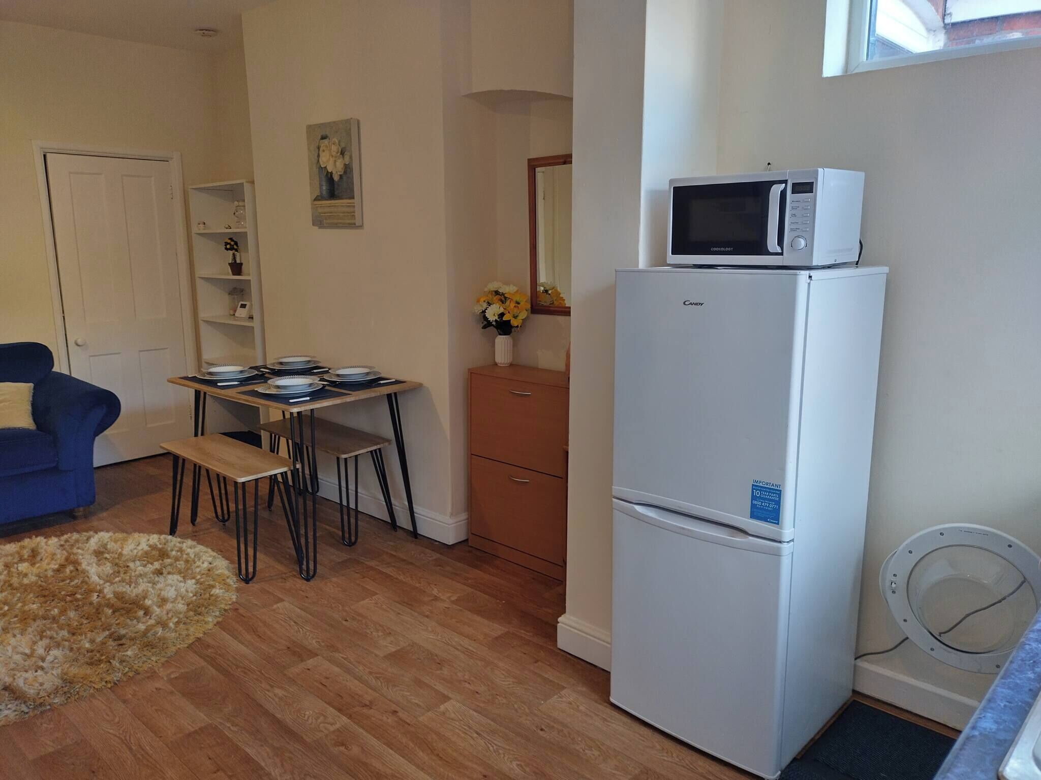 A compact living space with a kitchenette, a dining area, and a blue sofa.