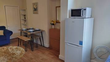 A compact living space with a kitchenette, a dining area, and a blue sofa.