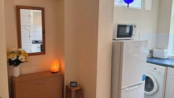 A compact kitchen with a microwave, toaster, and washing machine.
