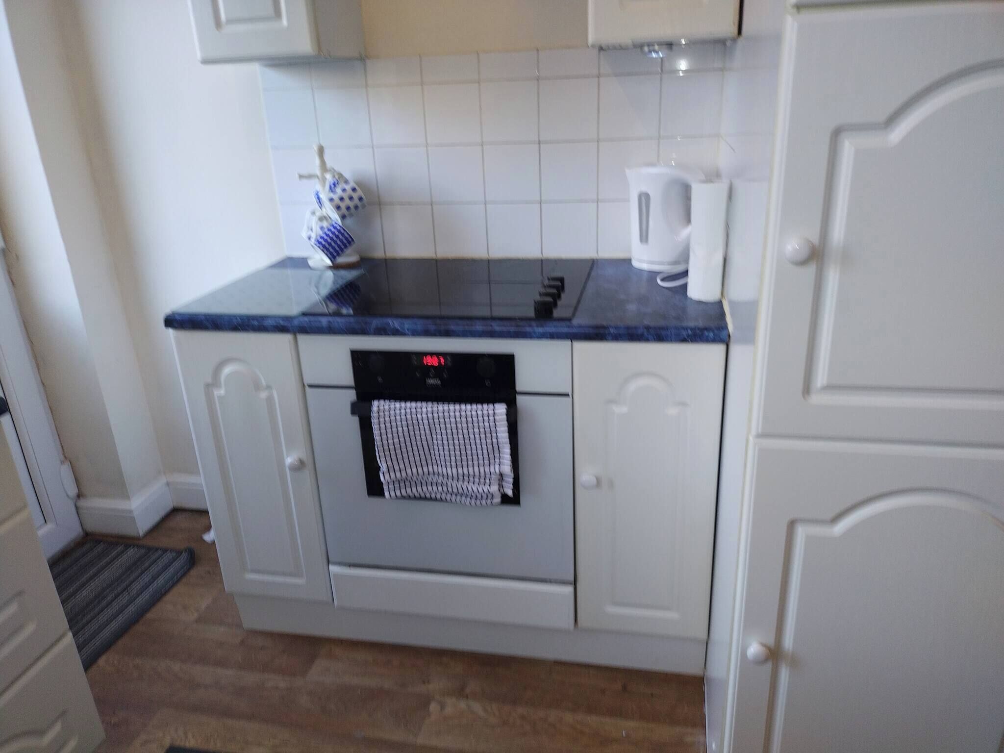 A kitchen with a built-in oven, a coffee maker, and a kettle on the countertop.