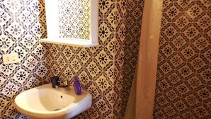 A bathroom with patterned walls, a sink, and a window. - Villa Opera - Apartment in Livorno (Toscana)