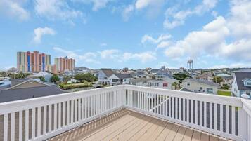 A balcony with a white railing overlooking a residential area with houses and a water tower.