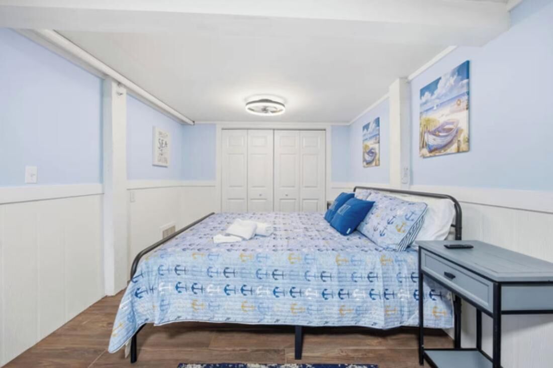 A bedroom with a bed, a desk, a wardrobe, and a ceiling light.