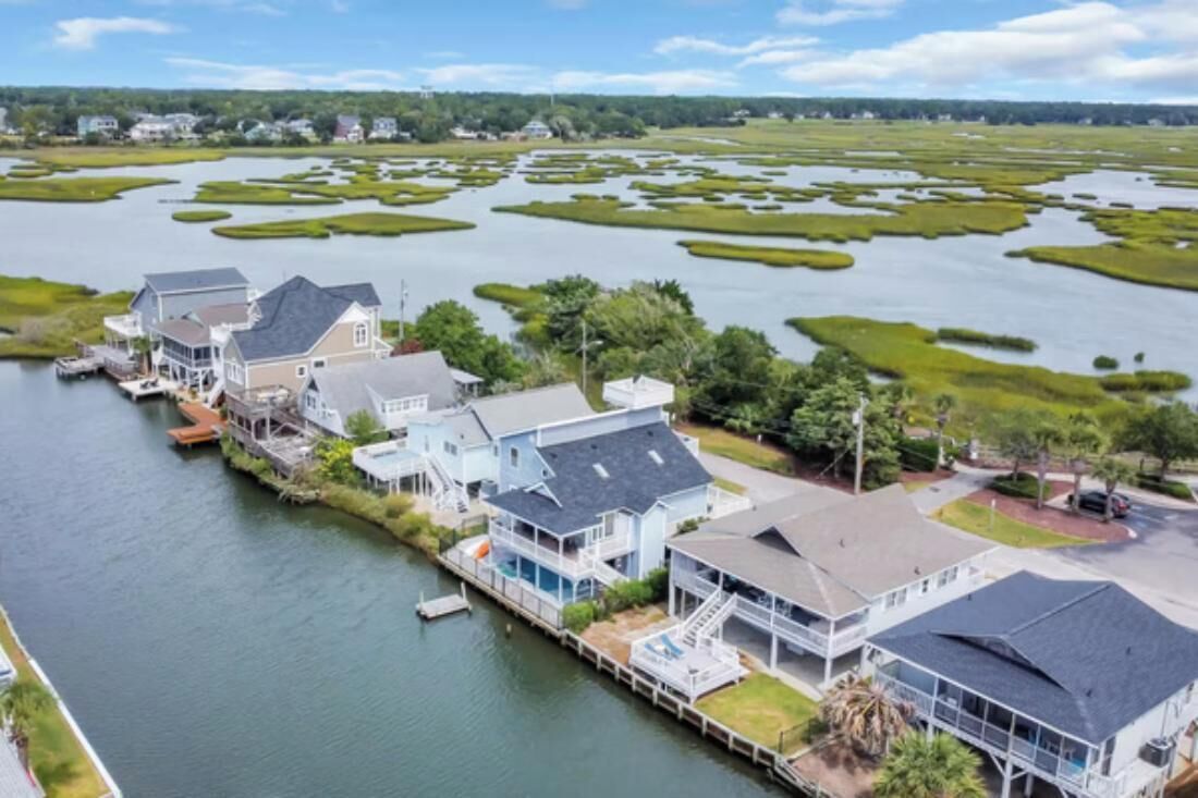 Une propriété située au bord de l’eau, comprenant plusieurs maisons reliées par des quais et entourée d’un paysage marécageux.
