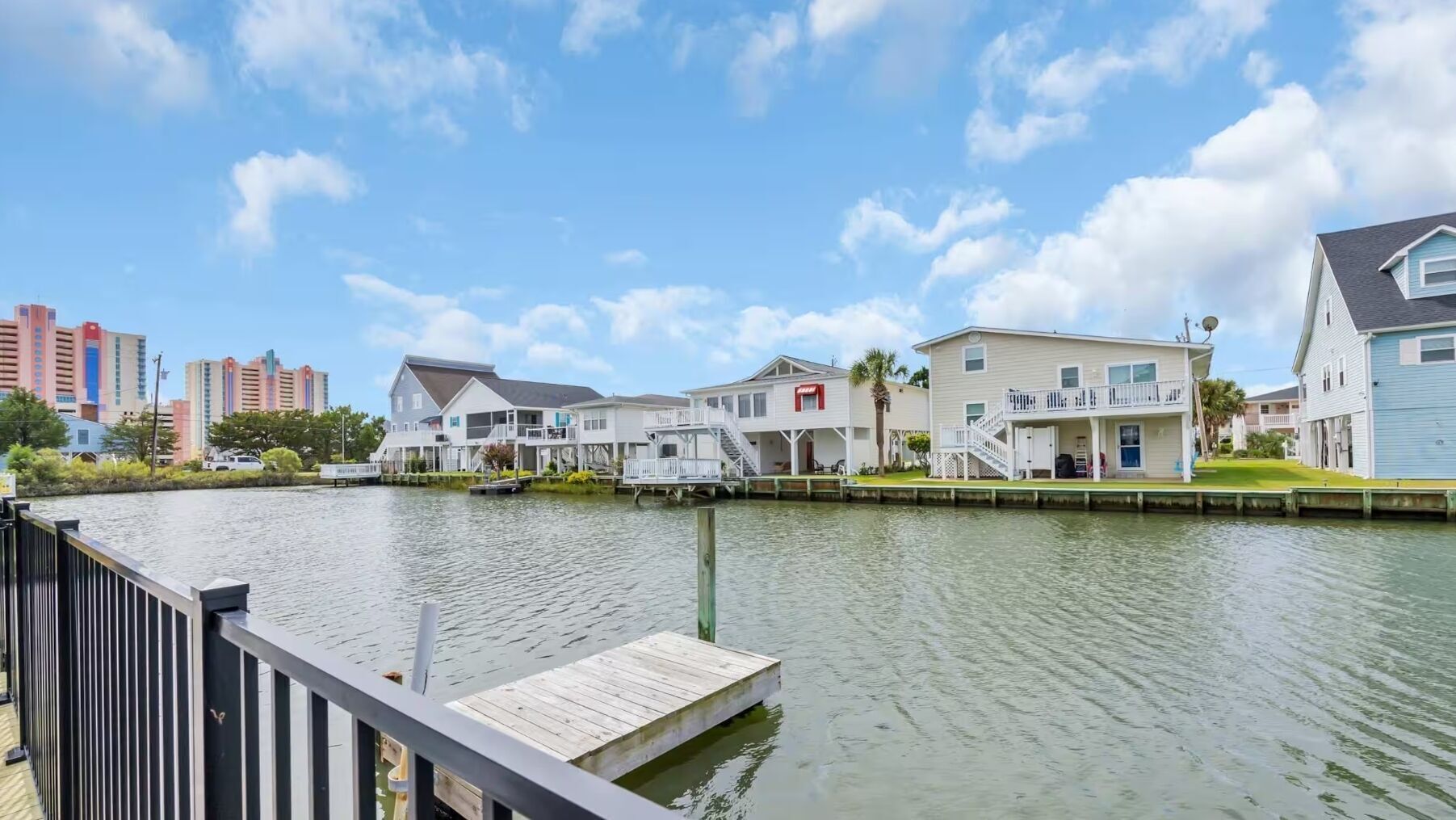 A waterfront property with multiple houses, a dock, and a cityscape in the background.