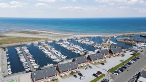 Un port de plaisance avec des bateaux amarrés, un espace de stationnement et des bâtiments aux toits rouges.