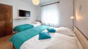 Ein Hotelzimmer mit zwei Betten, einem an der Wand befestigten Fernseher und einem fenster mit Vorhängen.