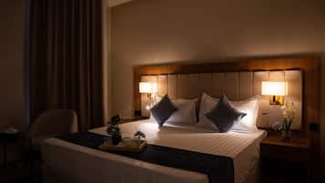 A hotel room with a large bed, two bedside lamps, a nightstand with a vase of flowers, and a chair.